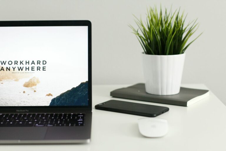Clean desk setup featuring laptop smartphone and plant Website Support in Eccles